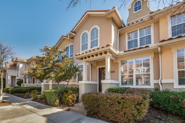 mediterranean / spanish home with a tiled roof and stucco siding