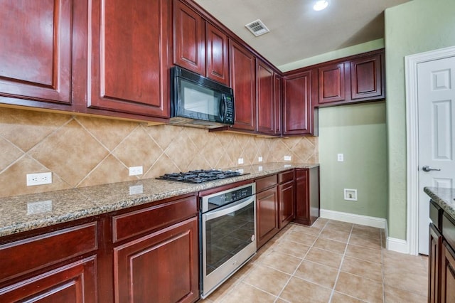 kitchen featuring visible vents, gas cooktop, reddish brown cabinets, black microwave, and stainless steel oven