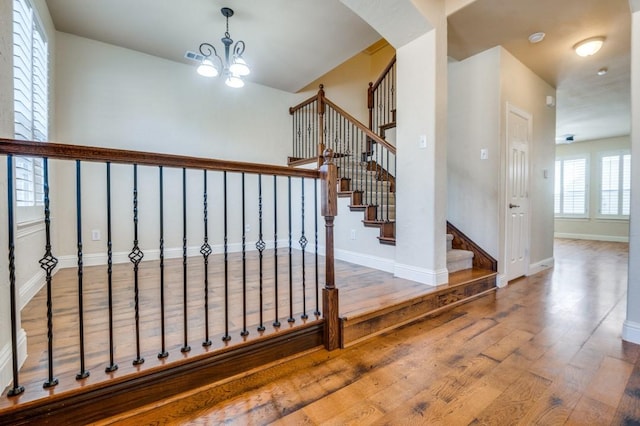 staircase with visible vents, baseboards, an inviting chandelier, wood finished floors, and arched walkways