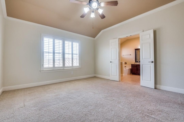 unfurnished bedroom with lofted ceiling, ornamental molding, ensuite bath, baseboards, and light colored carpet