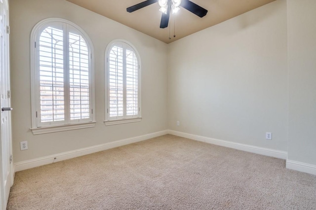 carpeted empty room with baseboards and a ceiling fan