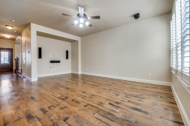 unfurnished living room featuring wood finished floors, baseboards, and ceiling fan