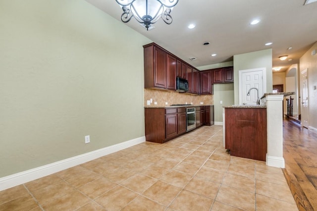 kitchen featuring light tile patterned floors, light stone countertops, oven, black microwave, and backsplash