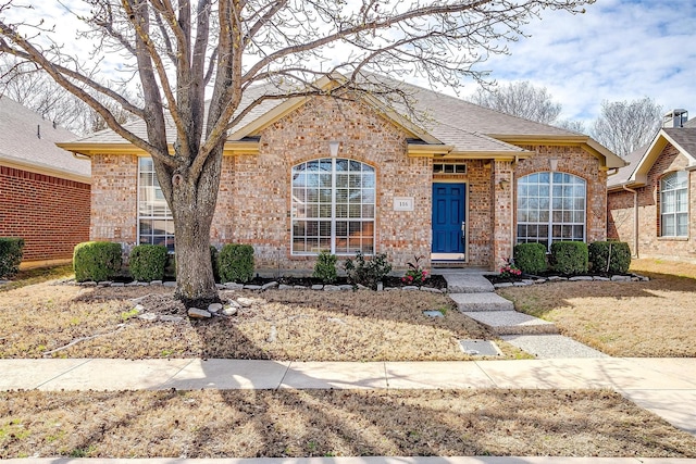 ranch-style home with brick siding and roof with shingles