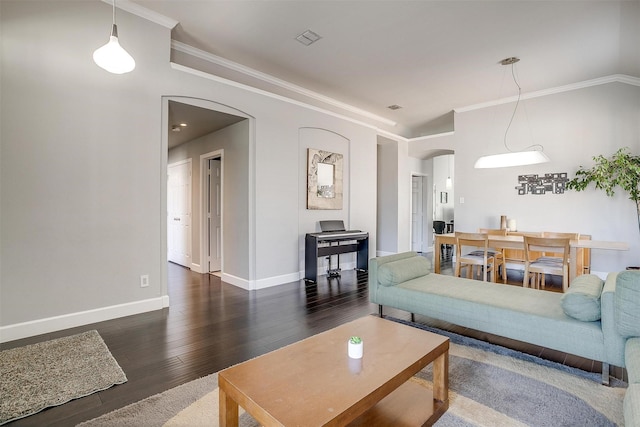 living area featuring wood finished floors, visible vents, baseboards, arched walkways, and ornamental molding