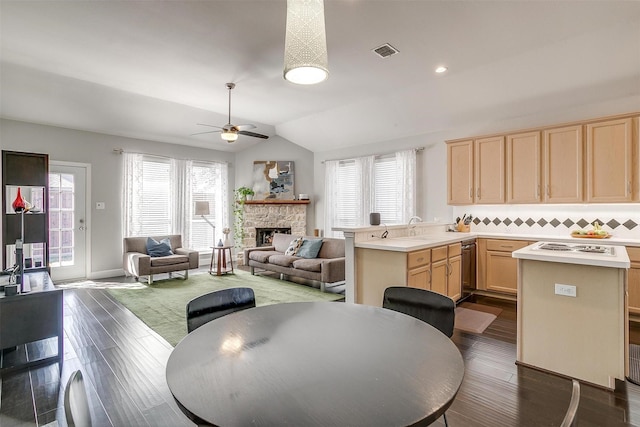 dining area with visible vents, dark wood-type flooring, a fireplace, ceiling fan, and vaulted ceiling