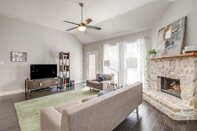 living area featuring a stone fireplace, lofted ceiling, wood finished floors, and ceiling fan