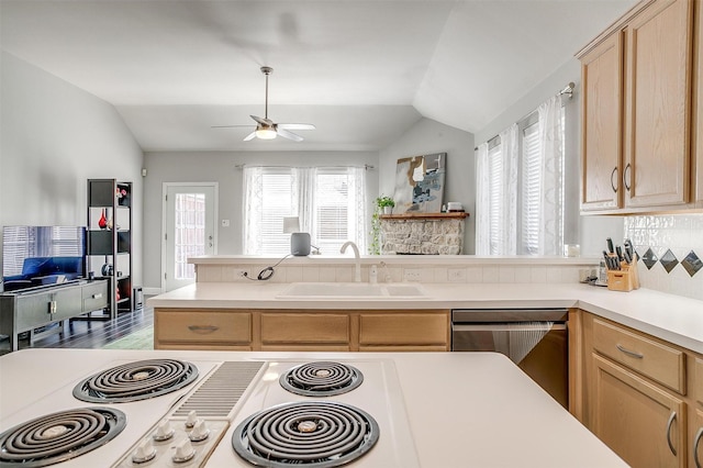 kitchen featuring a sink, stainless steel dishwasher, light brown cabinetry, and vaulted ceiling