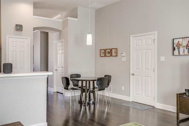 dining room with arched walkways, visible vents, dark wood-type flooring, and baseboards