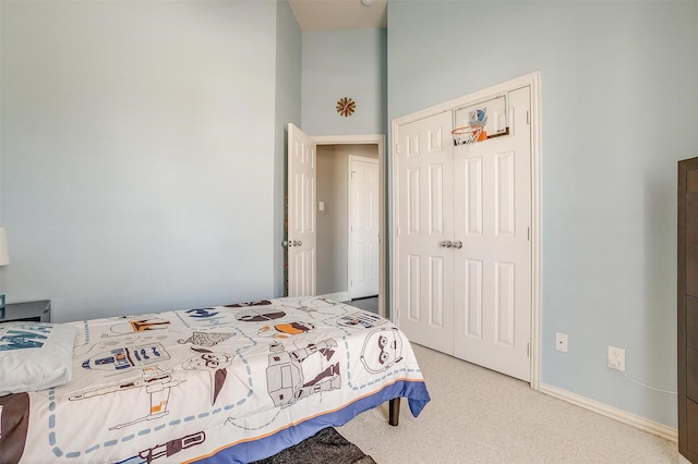 carpeted bedroom with a closet and baseboards