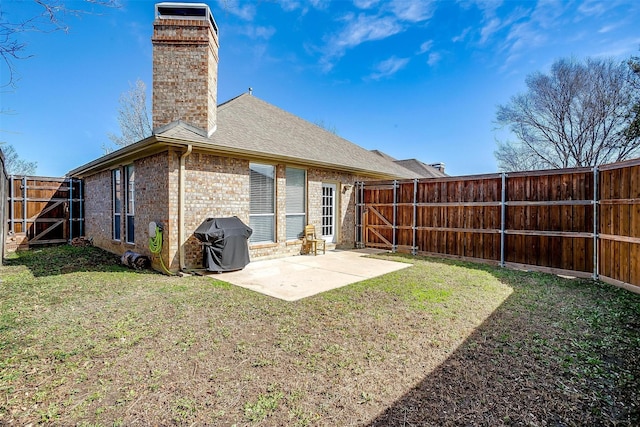 back of house featuring a patio, roof with shingles, a yard, a fenced backyard, and brick siding