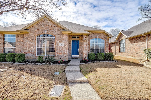 ranch-style home featuring brick siding and a shingled roof