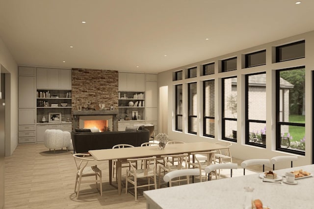 dining space with a stone fireplace, recessed lighting, and light wood-style floors