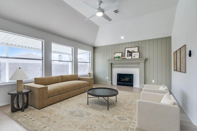 living room featuring lofted ceiling, a fireplace, visible vents, and a wealth of natural light