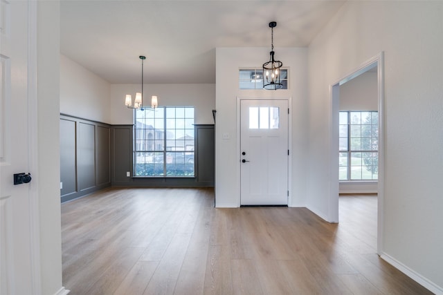 foyer with a notable chandelier, light wood-style flooring, and baseboards