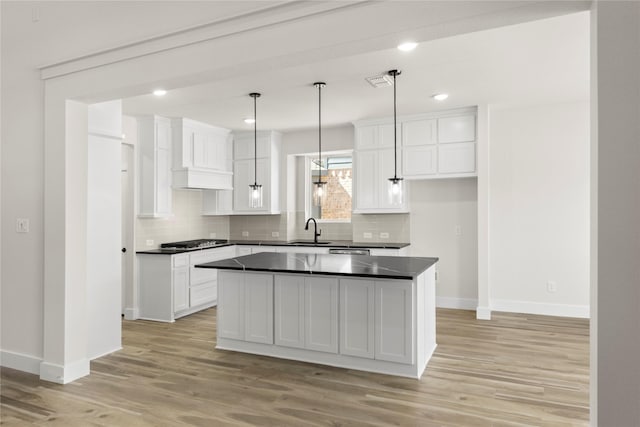 kitchen featuring gas stovetop, a sink, white cabinetry, dark countertops, and light wood-type flooring