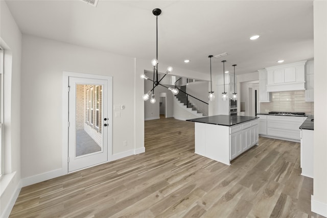 kitchen featuring dark countertops, decorative backsplash, light wood finished floors, and stainless steel gas cooktop