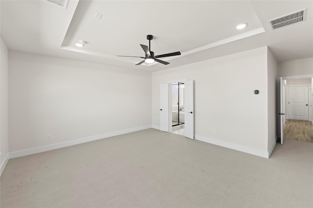 unfurnished bedroom with visible vents, baseboards, light colored carpet, a tray ceiling, and recessed lighting