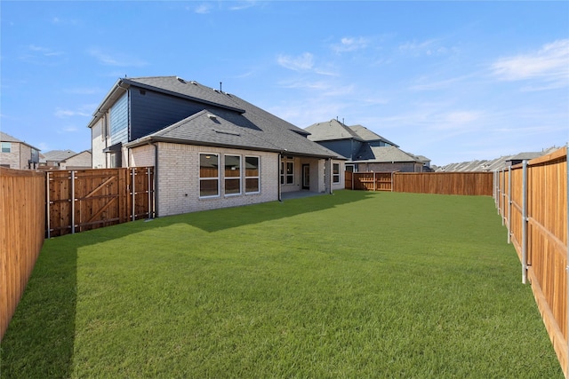 back of house featuring a yard, a fenced backyard, and brick siding