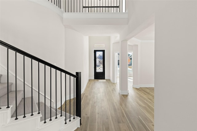 foyer with stairway, baseboards, a high ceiling, and wood finished floors