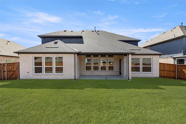 rear view of house featuring a yard, a fenced backyard, brick siding, and roof with shingles