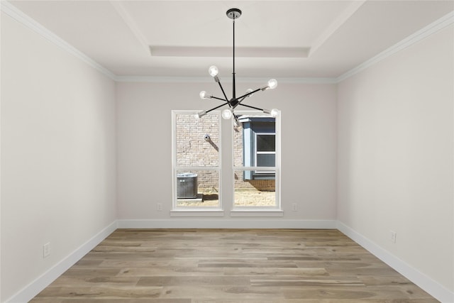 unfurnished dining area with a tray ceiling, baseboards, a notable chandelier, and light wood-style flooring