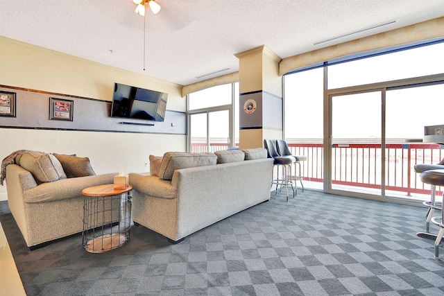 carpeted living area with a ceiling fan, a healthy amount of sunlight, visible vents, and a textured ceiling