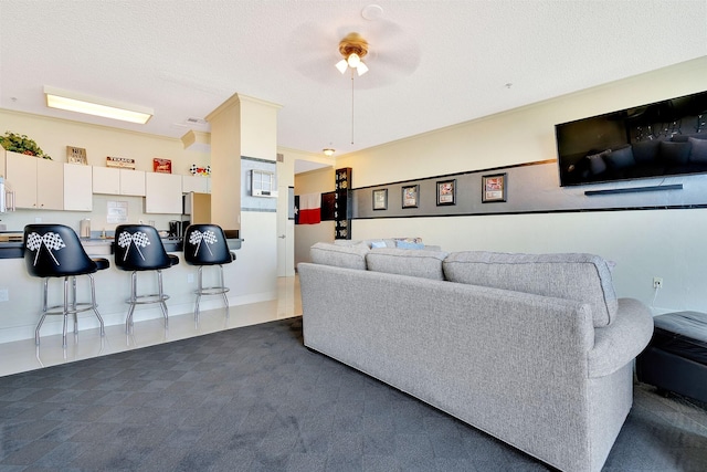 living area with dark carpet, a textured ceiling, a ceiling fan, and dark tile patterned flooring