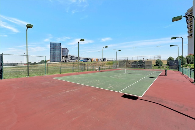 view of tennis court with community basketball court and fence