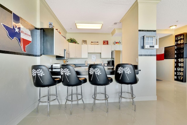 kitchen featuring white microwave, a peninsula, ornamental molding, and a textured ceiling