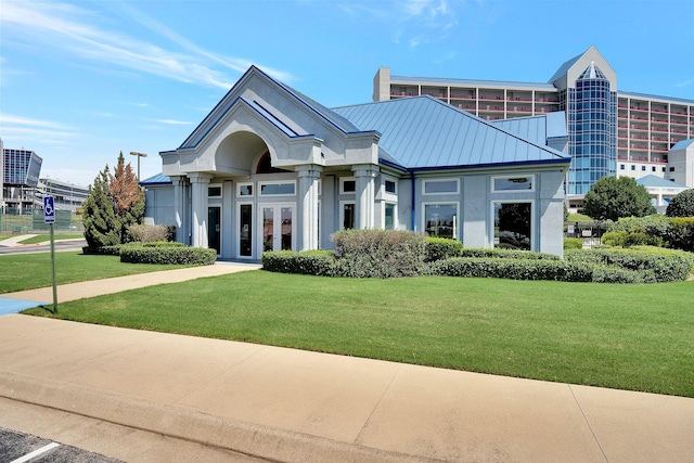 view of front of house featuring a standing seam roof, a front lawn, metal roof, and stucco siding