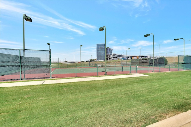 view of tennis court featuring a yard and fence