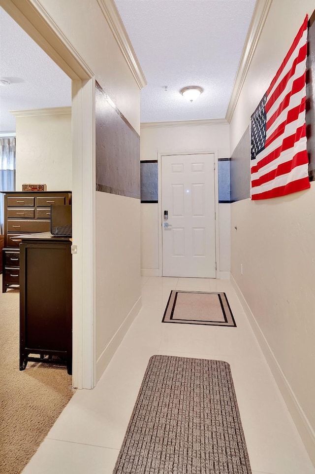 hall featuring a textured ceiling, baseboards, tile patterned flooring, and ornamental molding