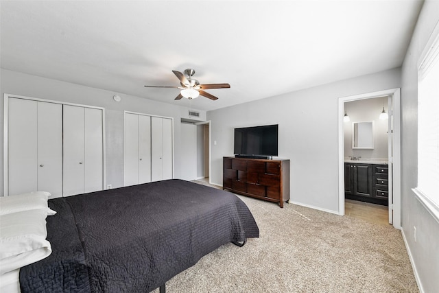 bedroom featuring baseboards, visible vents, ceiling fan, light carpet, and two closets