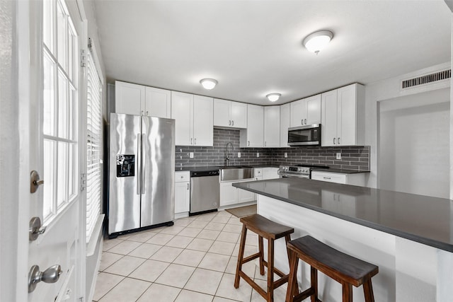 kitchen with backsplash, a breakfast bar area, light tile patterned flooring, stainless steel appliances, and a sink