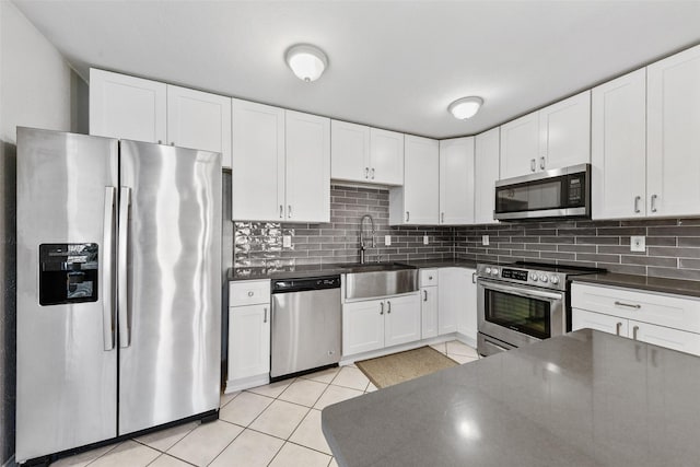 kitchen with dark countertops, light tile patterned flooring, stainless steel appliances, and a sink