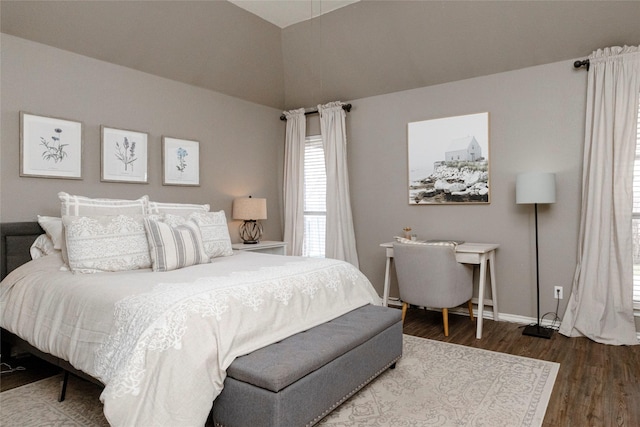 bedroom featuring baseboards, lofted ceiling, and wood finished floors