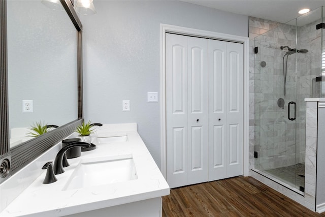 bathroom with a sink, wood finished floors, a stall shower, and double vanity