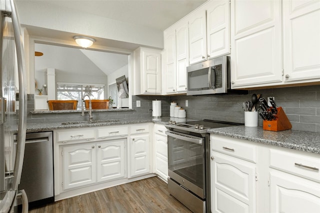 kitchen with backsplash, wood finished floors, appliances with stainless steel finishes, and a sink