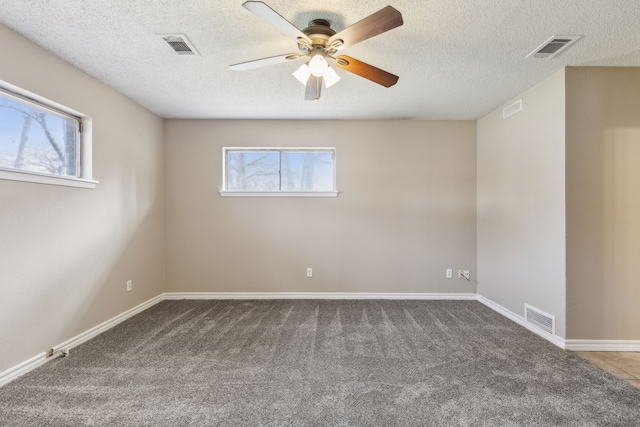 carpeted empty room featuring plenty of natural light, a ceiling fan, and visible vents