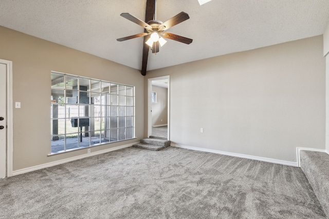 carpeted empty room featuring a textured ceiling, baseboards, lofted ceiling, and ceiling fan