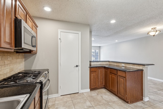 kitchen featuring stainless steel appliances, brown cabinets, a peninsula, and decorative backsplash