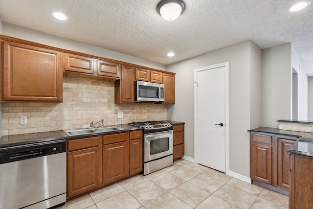 kitchen with a sink, dark countertops, stainless steel appliances, brown cabinetry, and decorative backsplash