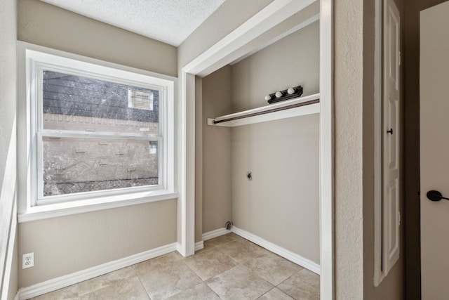 washroom with baseboards, laundry area, electric dryer hookup, a textured ceiling, and tile patterned floors