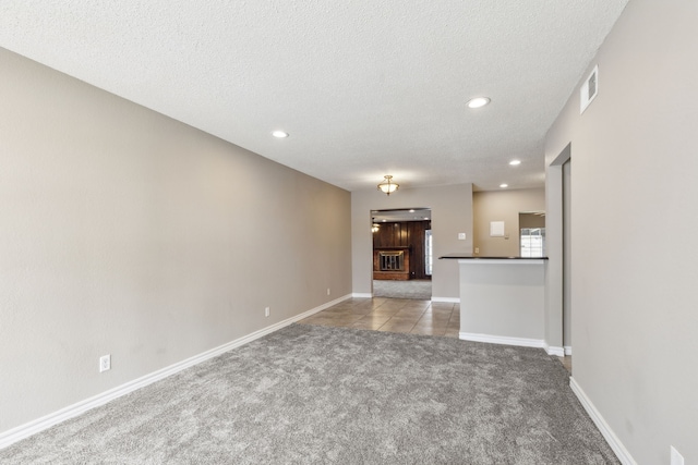 unfurnished living room featuring recessed lighting, baseboards, carpet floors, and a textured ceiling