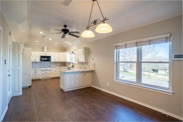 kitchen with vaulted ceiling, backsplash, black microwave, and a sink