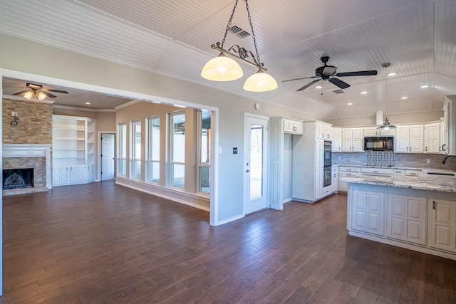 kitchen with open floor plan, a ceiling fan, black microwave, and a sink