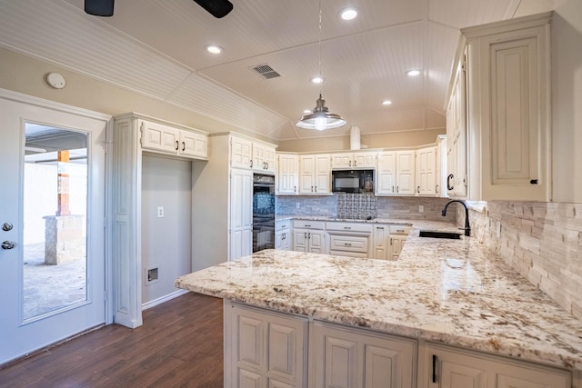 kitchen with light stone countertops, vaulted ceiling, a peninsula, black appliances, and a sink