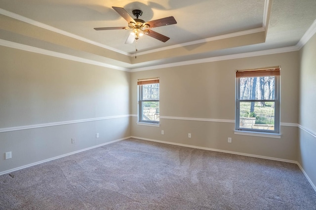 carpeted spare room featuring ceiling fan, baseboards, a tray ceiling, and ornamental molding