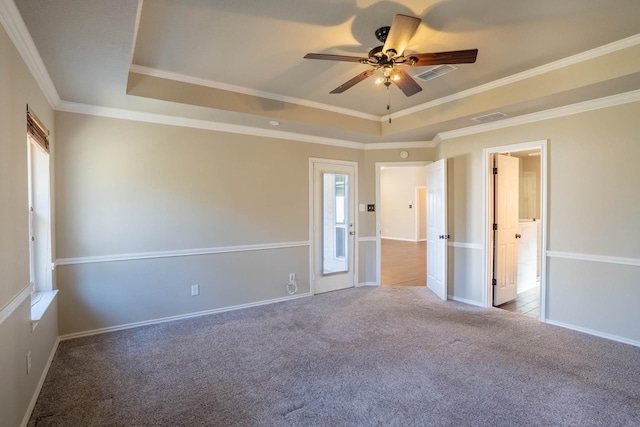 carpeted empty room with visible vents, a raised ceiling, and ceiling fan